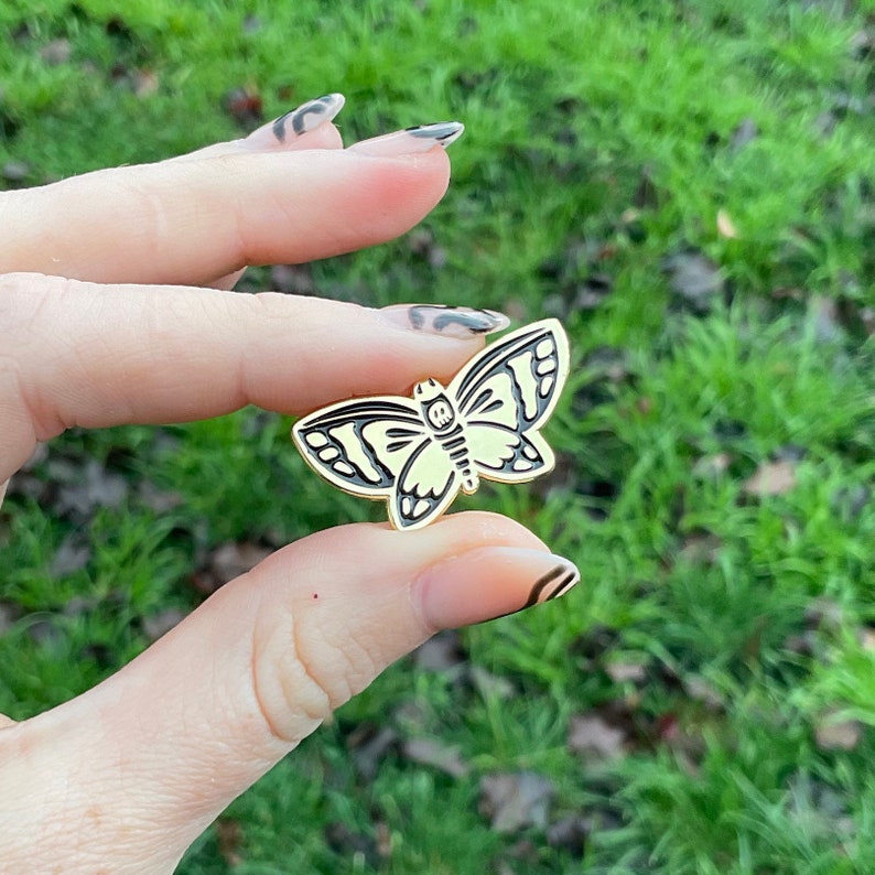Hand holds product showing front of lapel pin