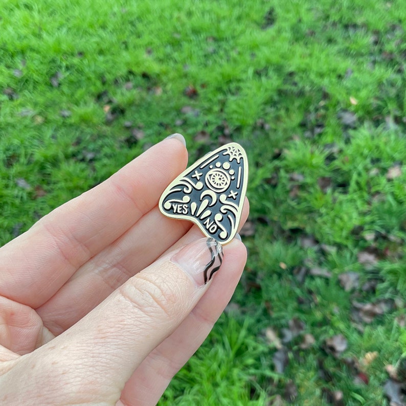 Hand holds product showing front of lapel pin