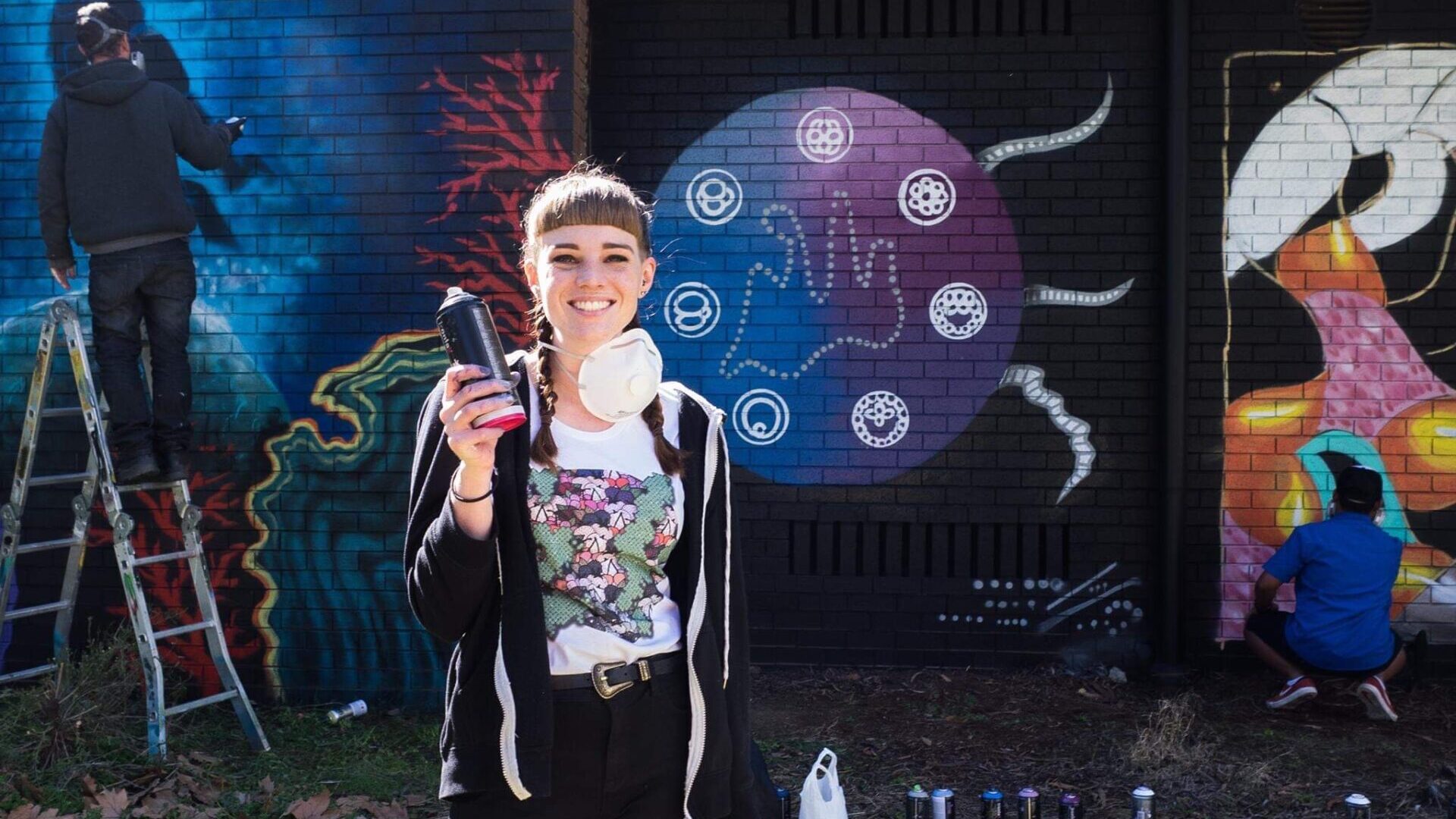 Girl smiles in front of scientific mural