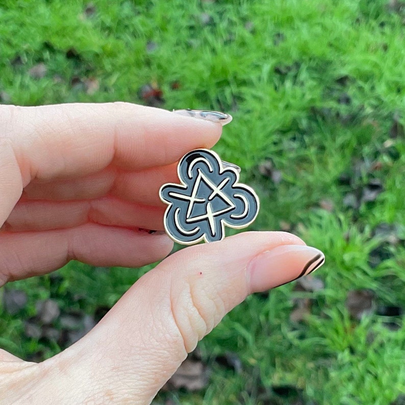 Hand holds product showing front of lapel pin