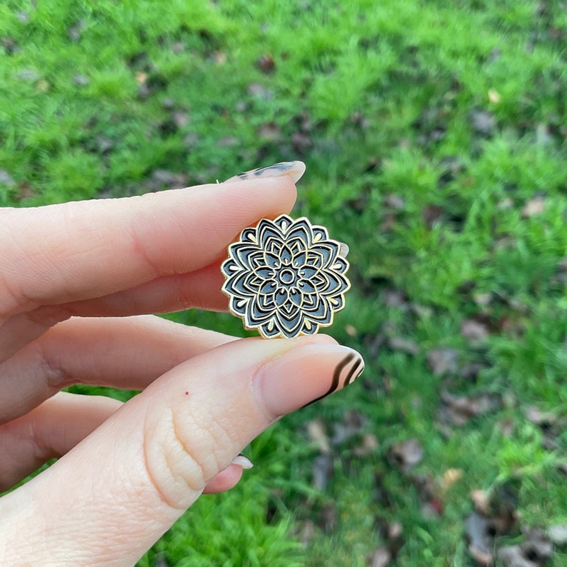 Hand holds product showing front of lapel pin